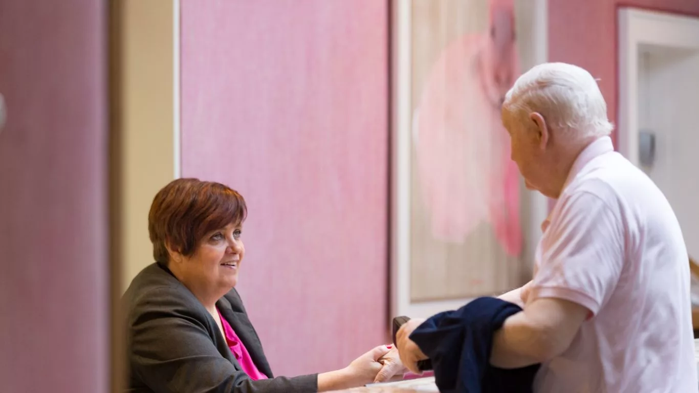 Friendly receptionist greets guest at hotel’s stylish lobby, offering warm hospitality and personalised check-in service.