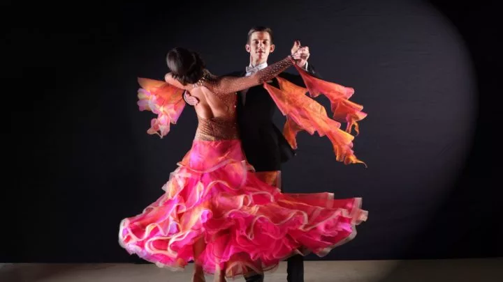 Elegant dancers in vibrant pink swirling gowns on stage. Enjoy live performances at our stylish and cultural hotel venue.