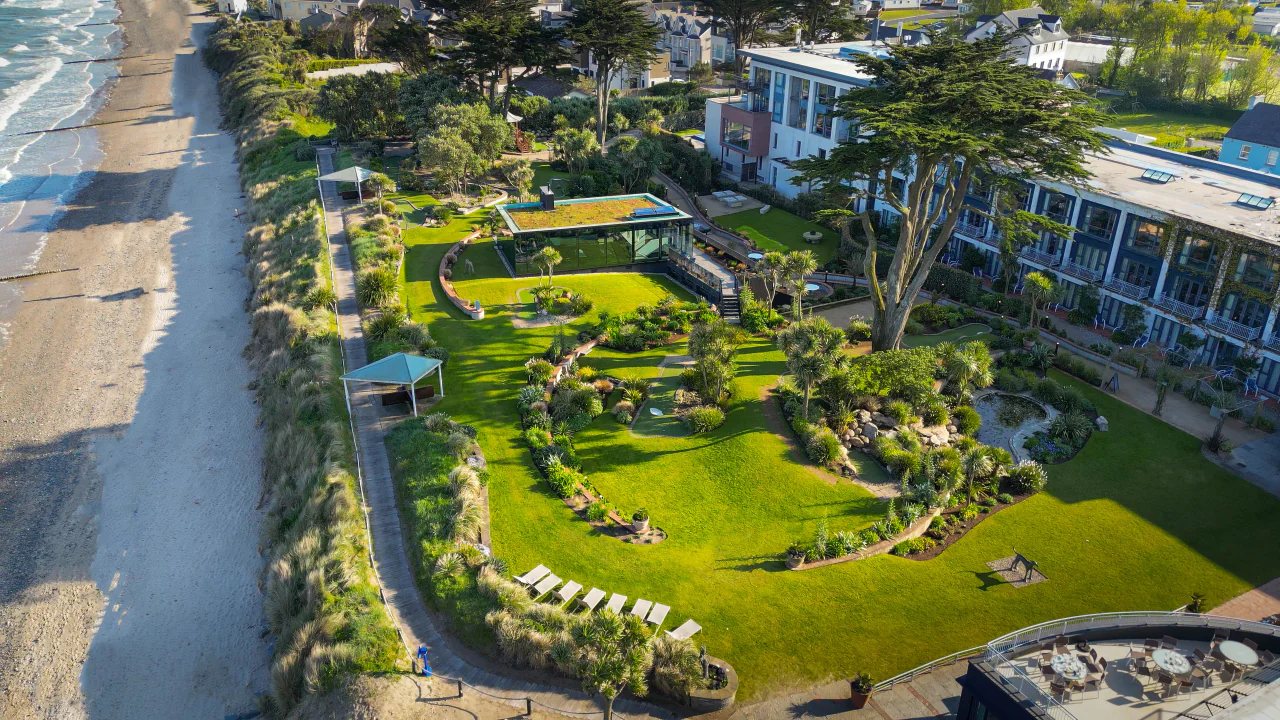 Coastal hotel with lush gardens, beachfront walkway, sun loungers, and ocean views create a serene getaway experience.