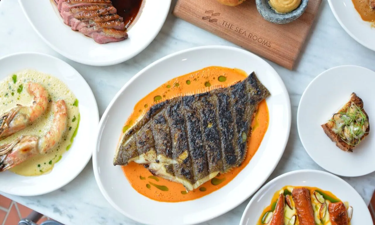 Delicious seafood dishes elegantly presented, including grilled fish and prawns, showcasing the hotel's gourmet dining experience.