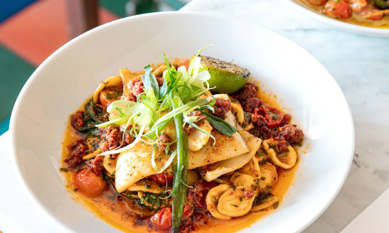 Savour delicious Italian pasta dish in chic hotel dining area with vibrant decor. Perfect for a culinary getaway.